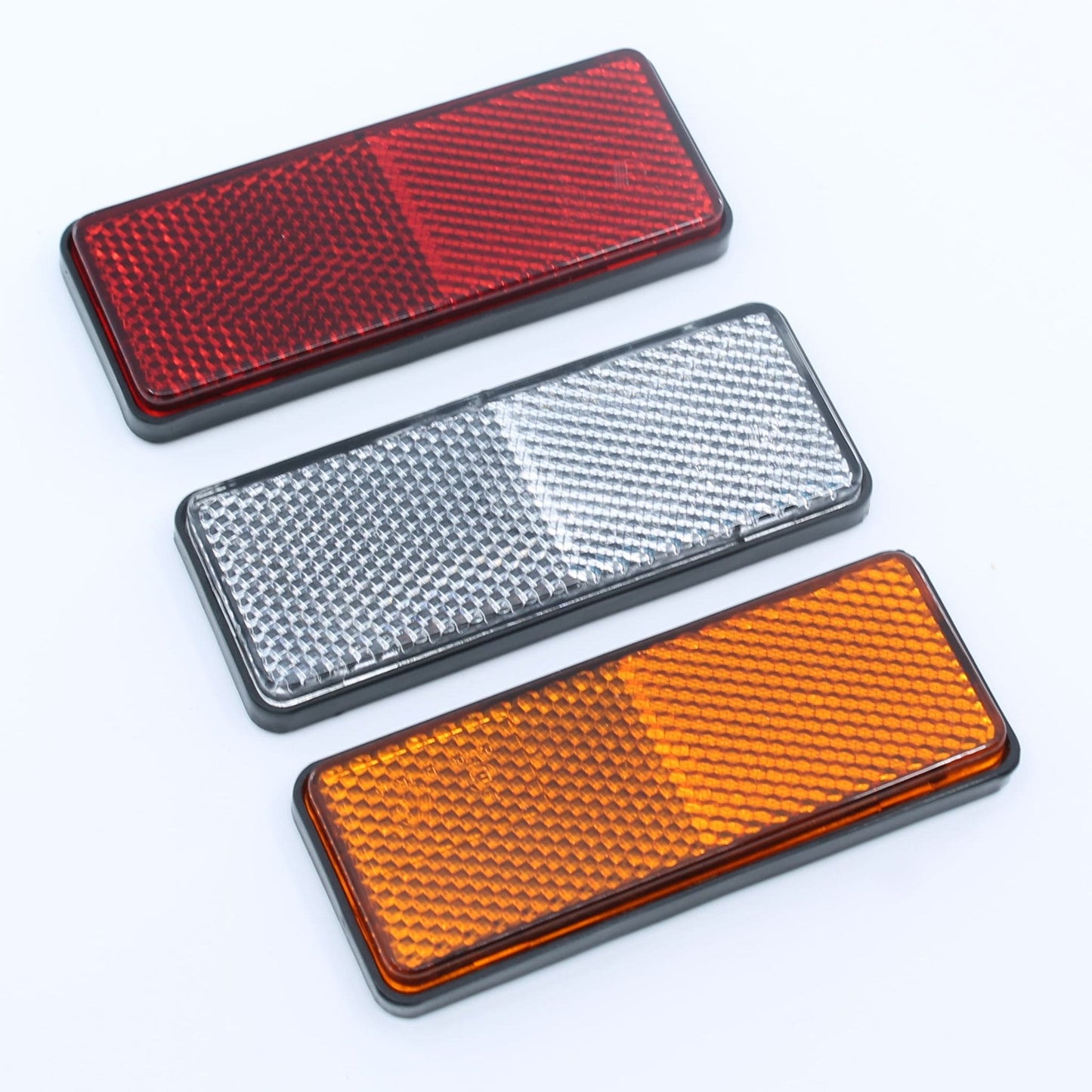 Conjunto de reflectores de seguridad de forma rectangular (rojo, ámbar y blanco), para montaje trasero con fijación adhesiva, utilizado en remolques y maquinaria agrícola.