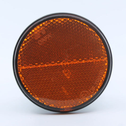 Reflector de seguridad de forma redonda y color ámbar (naranja), para montaje lateral con fijación adhesiva, utilizado en remolques y maquinaria agrícola.