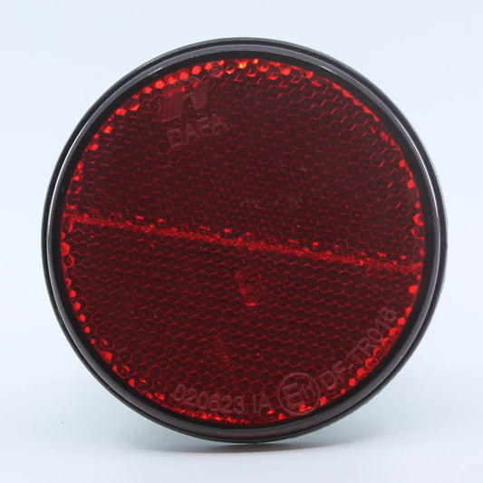 Reflector de seguridad de forma redonda y color rojo, para montaje trasero con fijación adhesiva, utilizado en remolques y maquinaria agrícola.