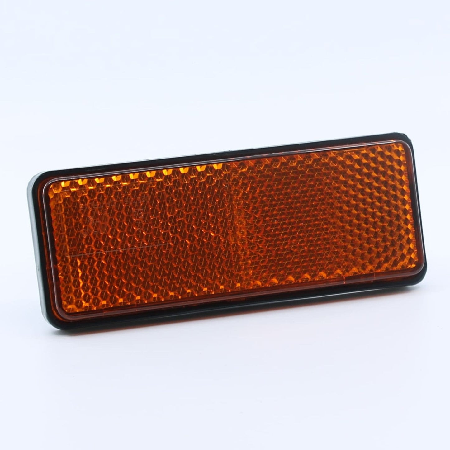 Reflector de seguridad de forma rectangular y color ámbar (naranja), para montaje lateral con fijación adhesiva, utilizado en remolques y maquinaria agrícola.