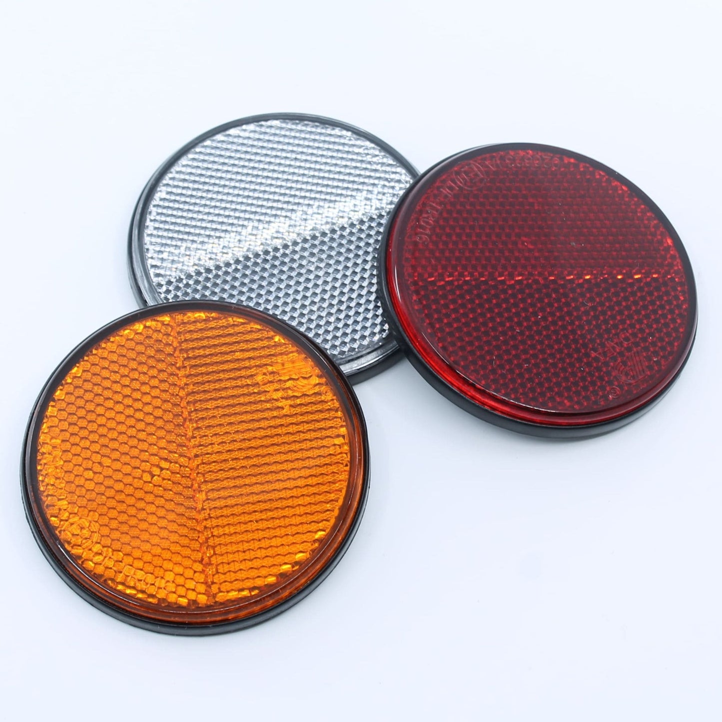 Reflector de seguridad de forma redonda y color rojo, para montaje trasero con fijación adhesiva, utilizado en remolques y maquinaria agrícola.