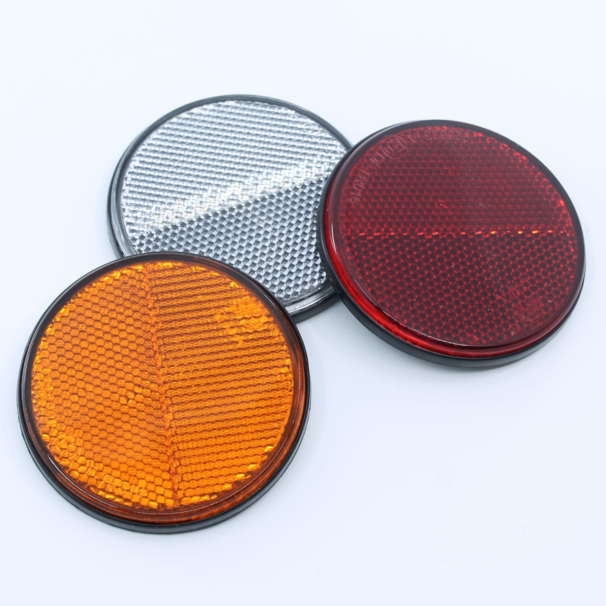 Reflector de seguridad de forma redonda y color rojo, para montaje trasero con fijación adhesiva, utilizado en remolques y maquinaria agrícola.
