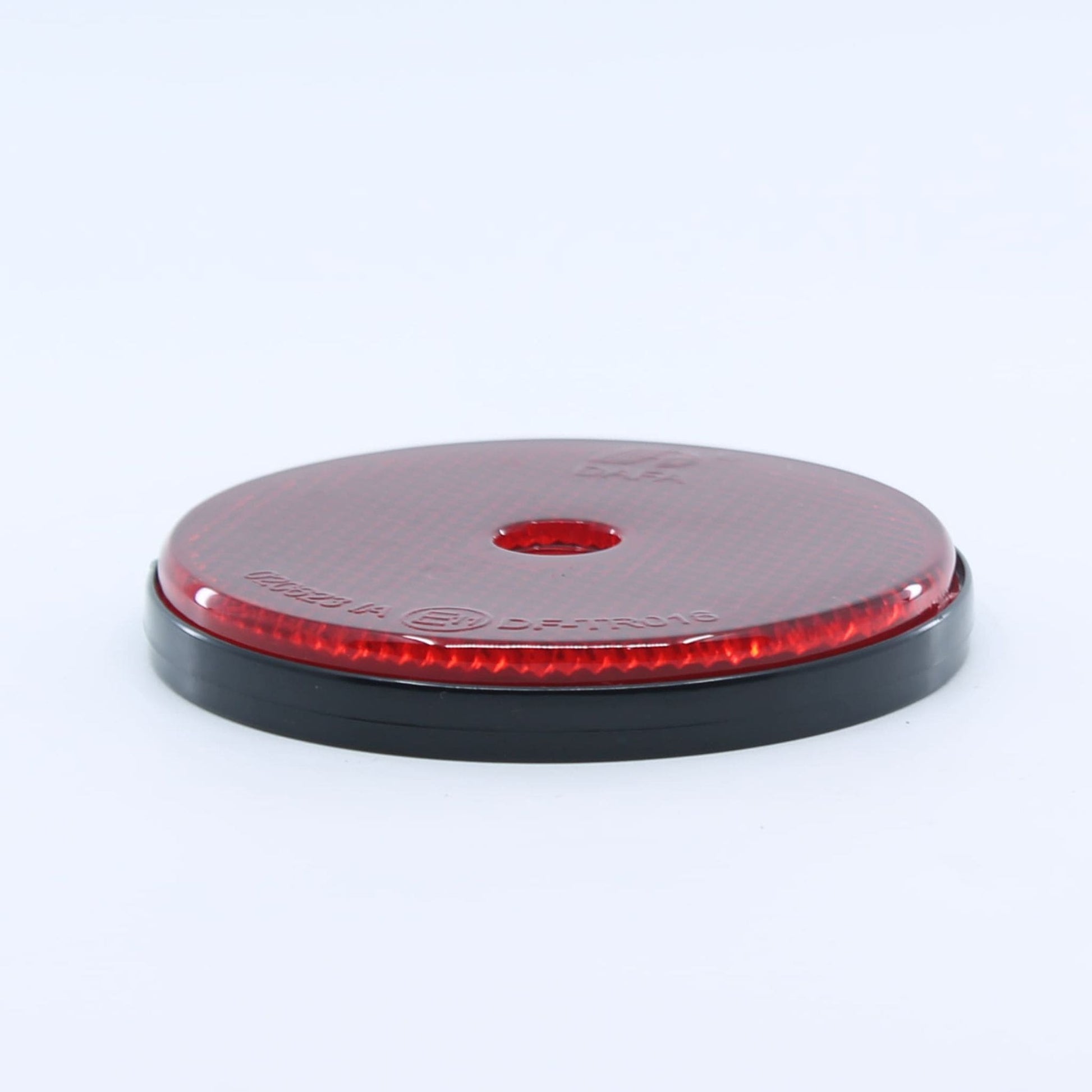 Reflector de seguridad de forma redonda y color rojo, con fijación de atornillar, utilizado como señalización trasera en remolques y maquinaria agrícola.
