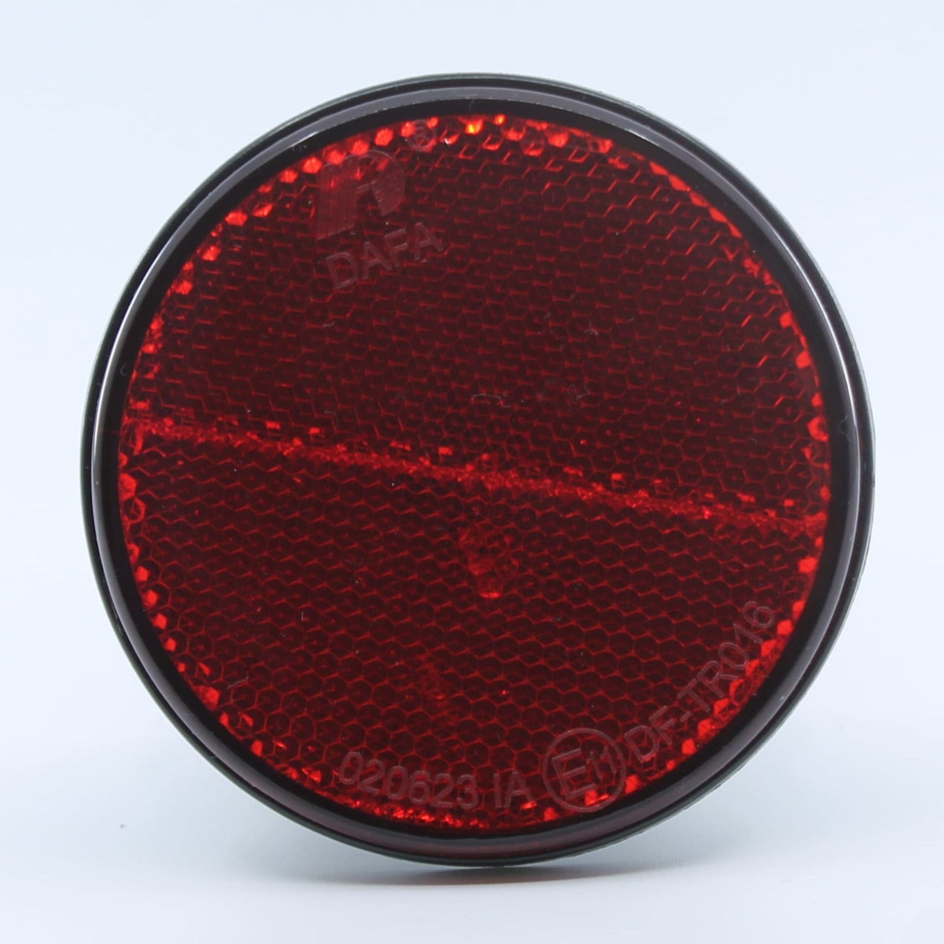 Reflector de seguridad de forma redonda y color rojo, para montaje trasero con fijación adhesiva, utilizado en remolques y maquinaria agrícola.