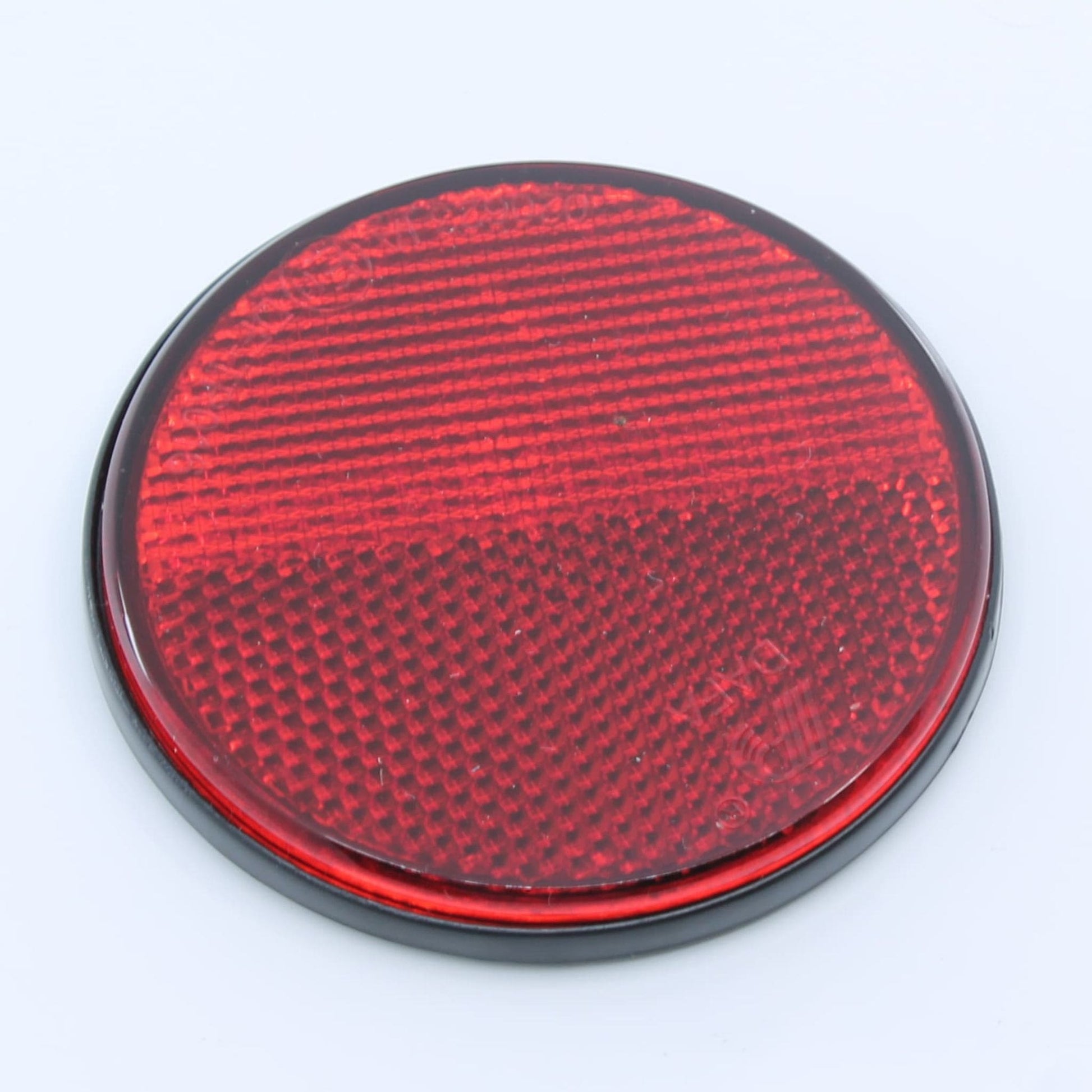 Reflector de seguridad de forma redonda y color rojo, para montaje trasero con fijación adhesiva, utilizado en remolques y maquinaria agrícola.